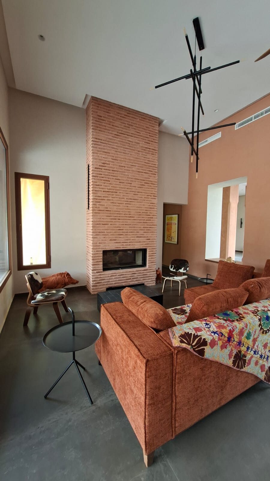 Cheminée à foyer fermé installée par Flamme Plus dans un salon double hauteur à Marrakech, habillage en brique